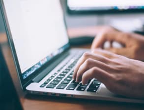 pair of hands typing on a laptop